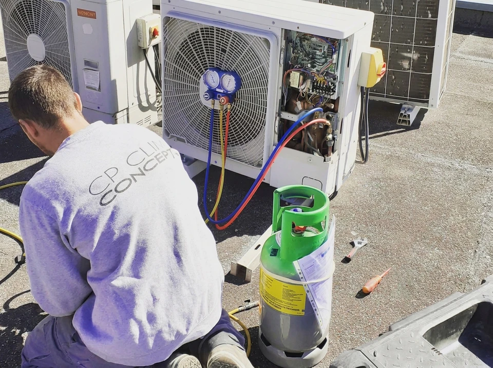 Technicien en veste grise effectuant la maintenance d'une unité extérieure de climatisation **Daikin Multi Inverter** sur façade