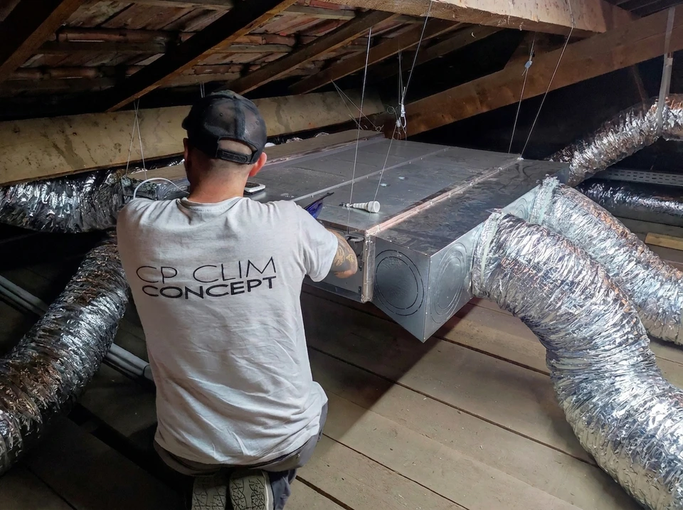 Technicien en veste grise effectuant la maintenance d'une unité extérieure de climatisation **Daikin Multi Inverter** sur façade