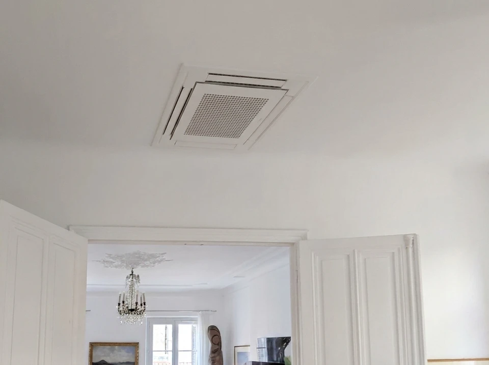 Technicien en veste grise effectuant la maintenance d'une unité extérieure de climatisation **Daikin Multi Inverter** sur façade