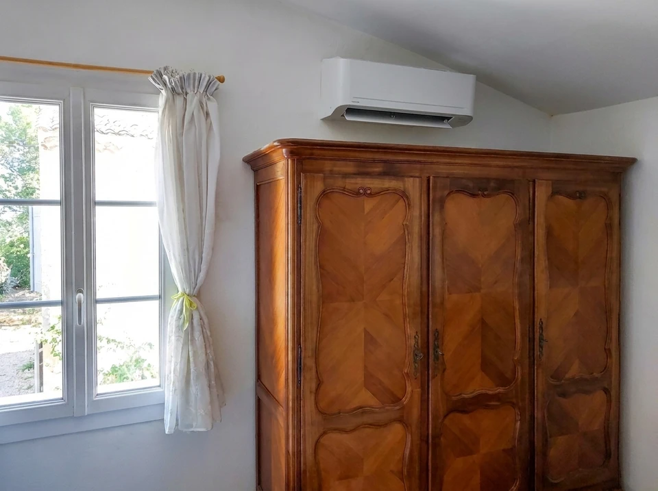Intérieur blanc épuré avec double porte à panneaux moulurés ouverte sur une salle à manger ornée d'un lustre à bougies en cristal et médaillon de plafond